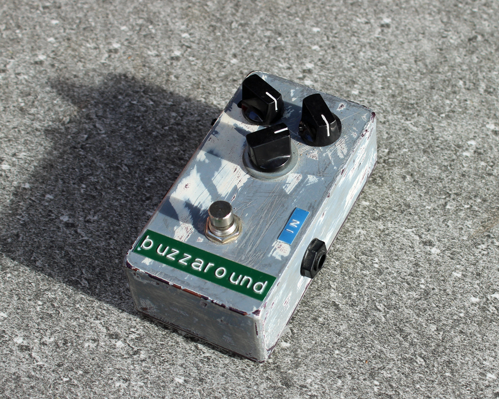 Hand-made fuzz pedal made of painted metal with dymo tape labeling, knobs and a switch, looks cute