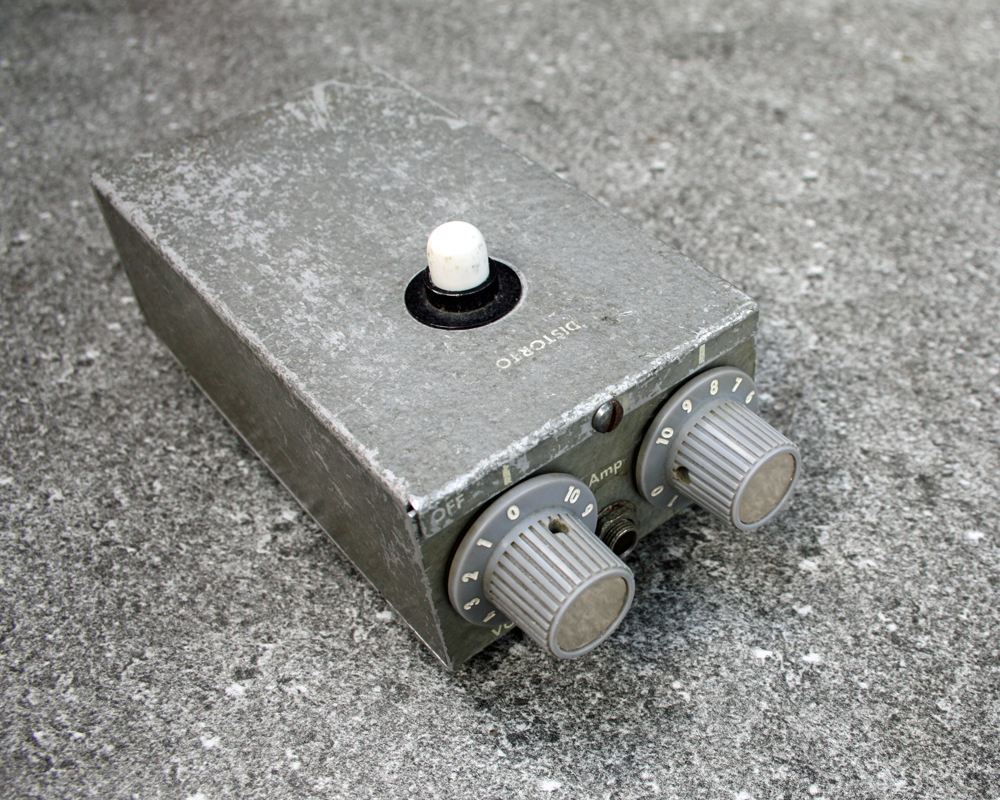 Vintage fuzz pedal, grey metal, extremely basic, two large knobs on the front and a switch on top, boxy