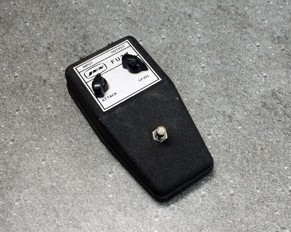 Vintage guitar fuzz pedal, black textured wedge shape with white label and Jen FUZZ branding, knobs and a switch