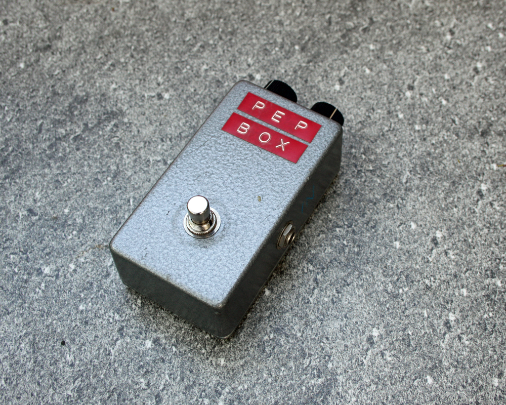 A hand made electronic pedal, neat little fuzzbox with a metal enclosure, minimal knobs and labelled in red dymo