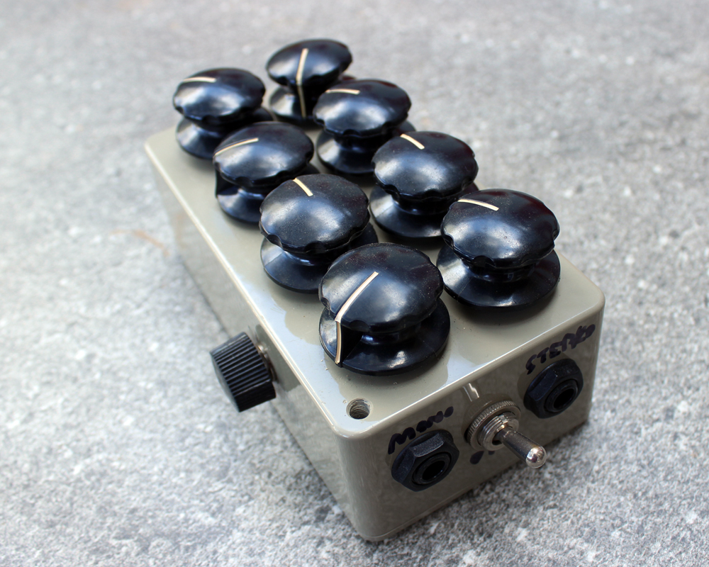 A weird-looking electronic effects box with eight knobs that are too big for the enclosure, making it look like a strange pastic and metal insect with a cheeky face