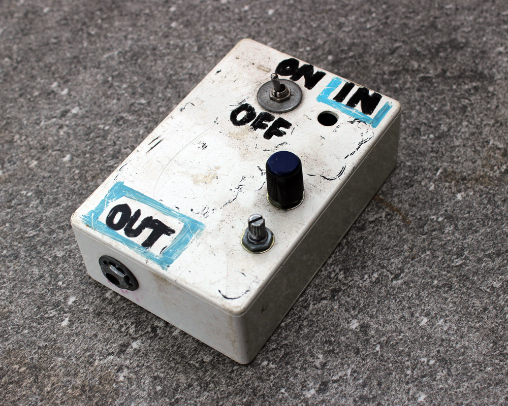 A hand made electronic pedal: metal, knobs and a switch, hand-written labels, fucked-up looking