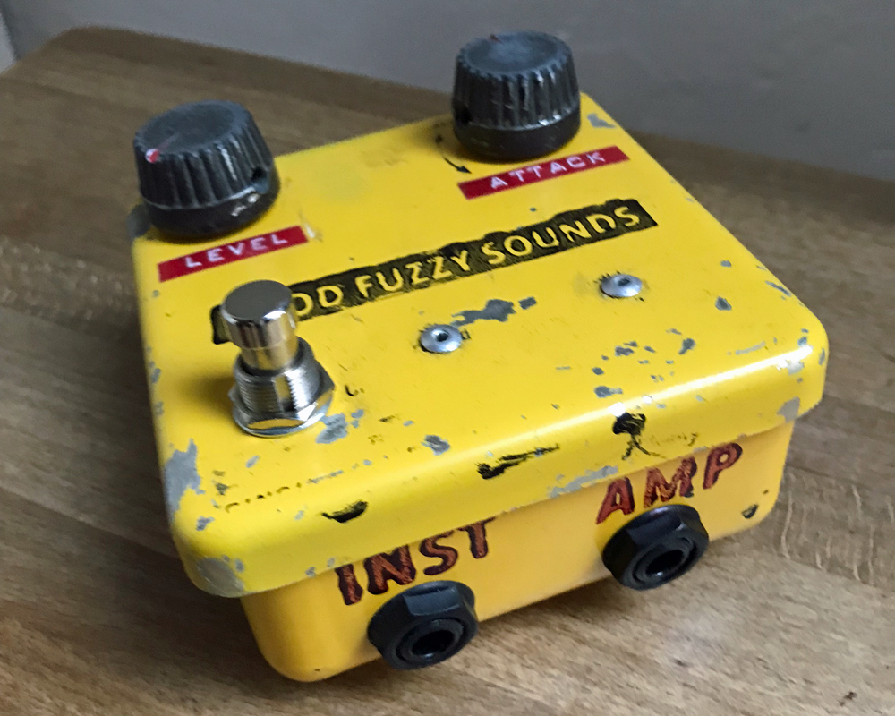 Good Fuzzy Sounds Bad Apple, a hand-made fuzz pedal in a metal enclosure painted yellow, with black plastic knobs, a switch, dymo tape and hand stamped labelling, slightly battered and worn