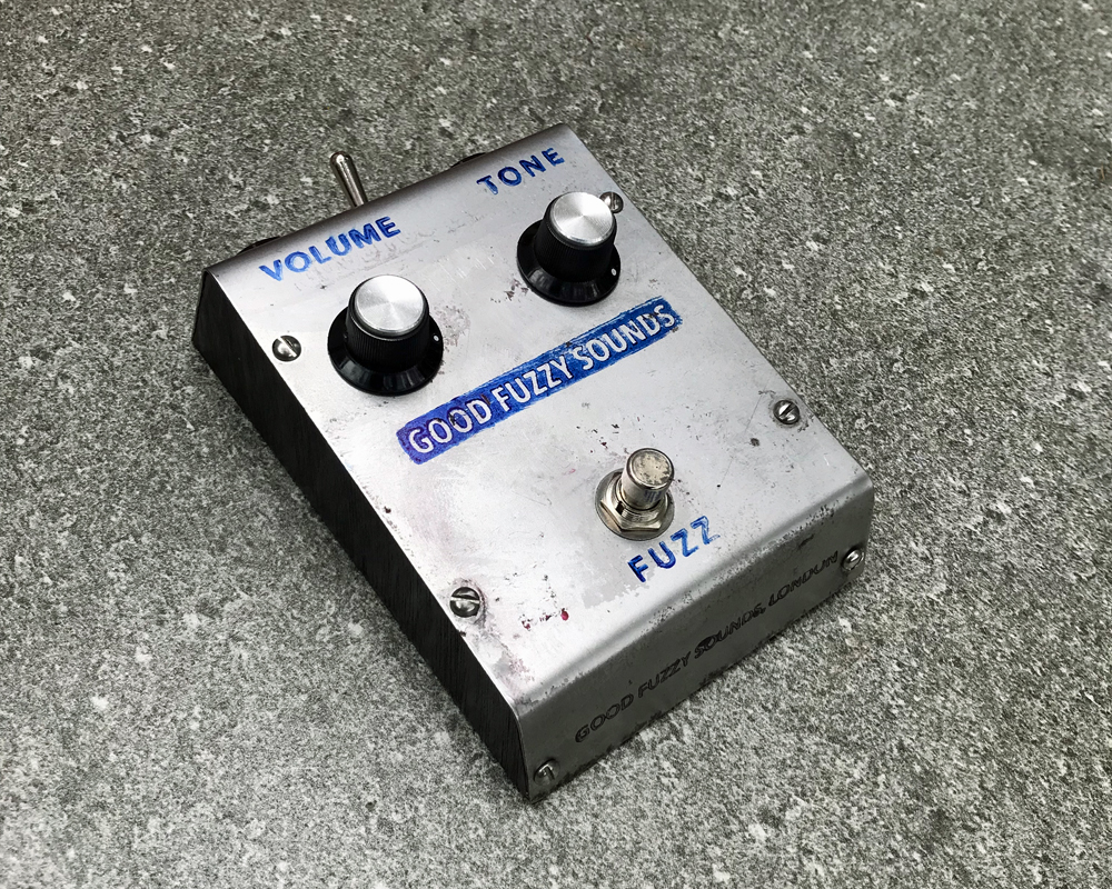 Good Fuzzy Sounds Bad Moon fuzz pedal, a wedge-shaped metal enclosure with two knobs, a foot switch and hand-stamped graphics, looks robotic and basic