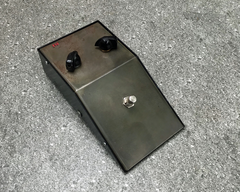 Good Fuzzy Sounds Bad Motorscooter, a prototype fuzz pedal, wedge-shaped metal with two knobs, a foot switch, extremely basic and malevolent-looking